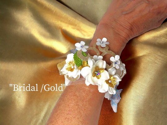 Gold themed light weight faux suede magnetic bracelet w/ hand made satin/silk Austrian Crystal and gold Lame' centered flowers , chiffon butterflies, delicate tulle, green silk and gold Lame' leaves, delicate skeleton leaves, gold scroll lace, gold lame' & white silk flowers w/ Austrian crystal centers are the backdrop for this beautiful bridal arm piece. 45.99