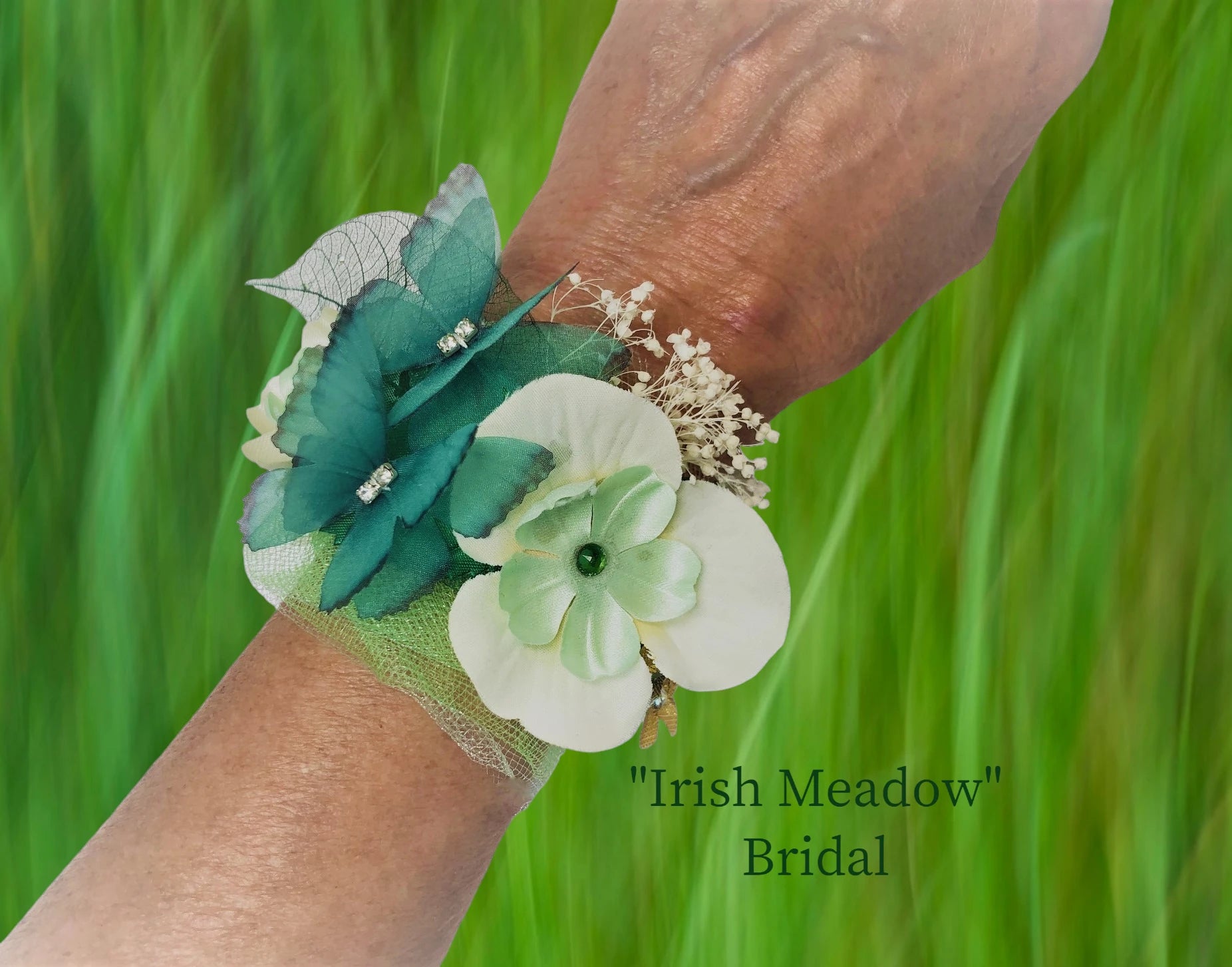 Irish Meadow- Bride's Maid- lightweight with magnetic closure. Beautiful Ivory Orchid, green silk flower, and green Austrian Crystal center. 2 chiffon butterflies, dried baby's breath, delicate green tulle, gold lame' flowers & leaves with Austrian Crystal centers and green skelelton leaves w/ crystal dew drops adorn this beautiful wedding arm piece. $47.99