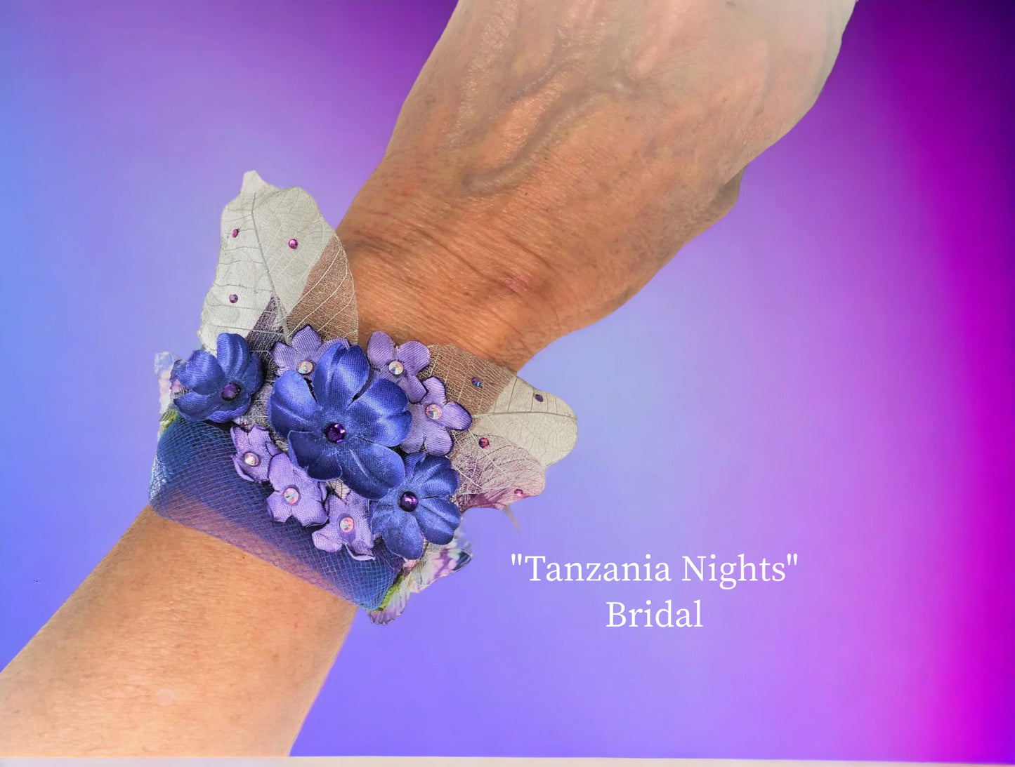 Tanzania Nights light weight magnetic closure. Tanzanite dark & light silk and silver lame' flowers w/ crystal centers, silver skeleton leaves w/ crystal dew drops, Tanzanite chiffon butterflies w/ rhinestone centers, green silk leaves, and delicate tanzanite tulle adorn this wedding bracelet. $43.99